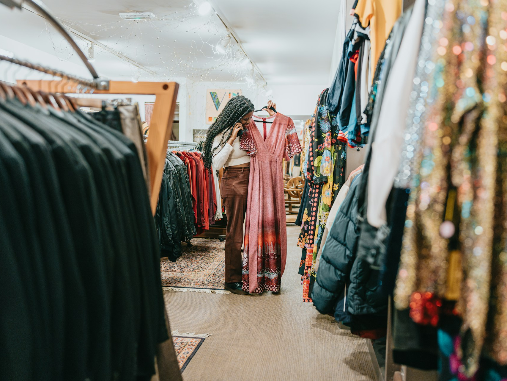 A lady in a retail clothing store is looking at dresses