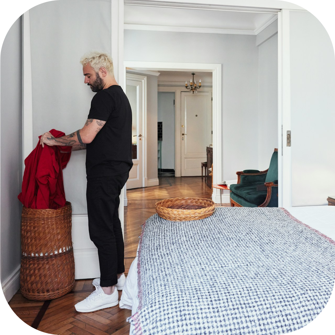 man cleaning up bedroom in apartment