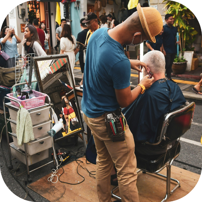 a barber cutting hair in the middle of a busy street