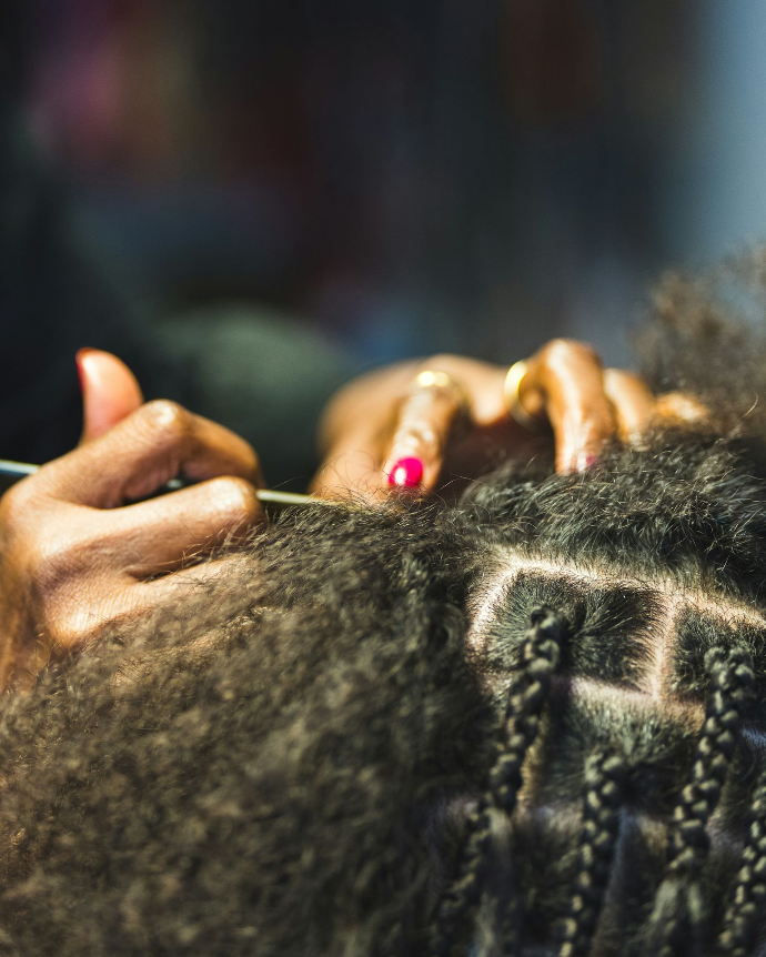 client getting her hair braided by hair braider
