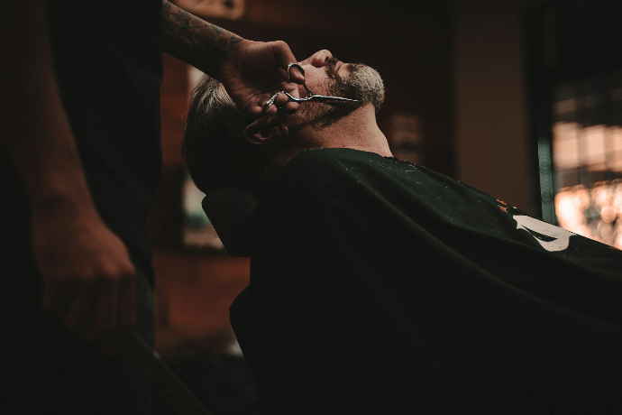 client in the chair getting his beard cut by barber